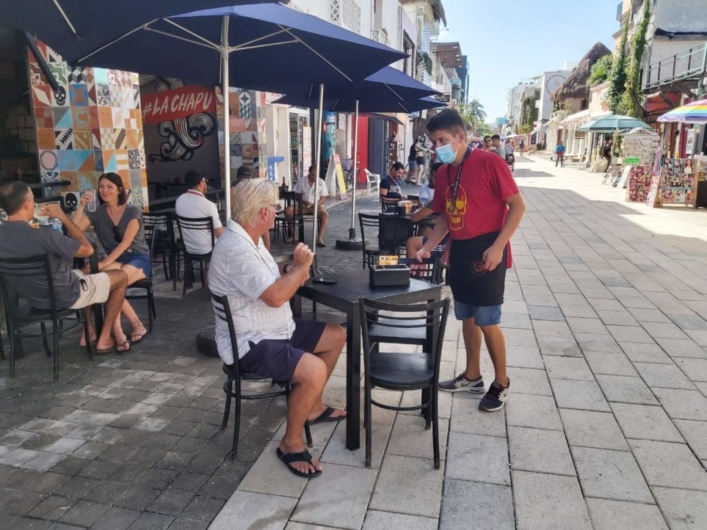 Con cubrebocas, turistas nacionales, extranjeros y residentes de Playa del Carmen pasean por este popular andador, entre comercios y restaurantes que aplican medidas sanitarias como entrega de gel antibacterial y toma de temperatura, entre otras.