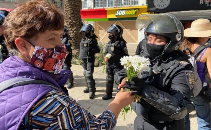 Mujeres policías reciben flores de manifestantes durante marcha del 8M