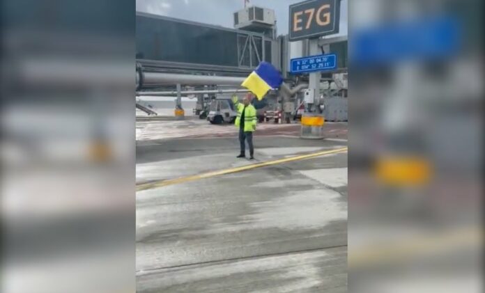 Empleado de aeropuerto da indicaciones a avión ruso con bandera de Ucrania