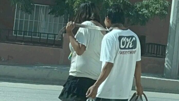 VIDEO: Mujer amarra con un cinturón a su pareja y lo pasea sonriente por las calles
