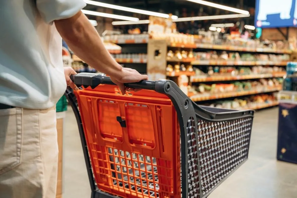 Persona empuja un carrito de compras en el pasillo de un supermercado