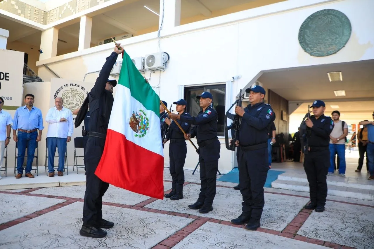Elementos de seguridad con la bandera de México en la ceremonia cívica en Playa del Carmen
